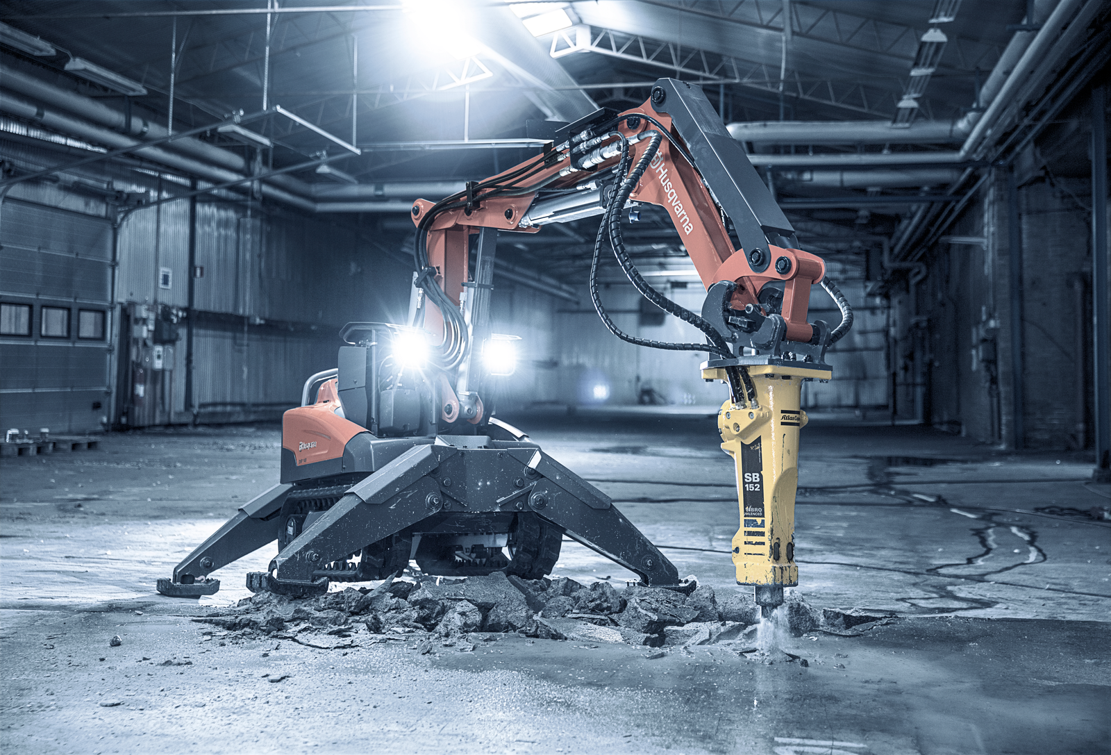 Husqvarna DXR with hydraulic breaker cutting a concrete floor in a warehouse